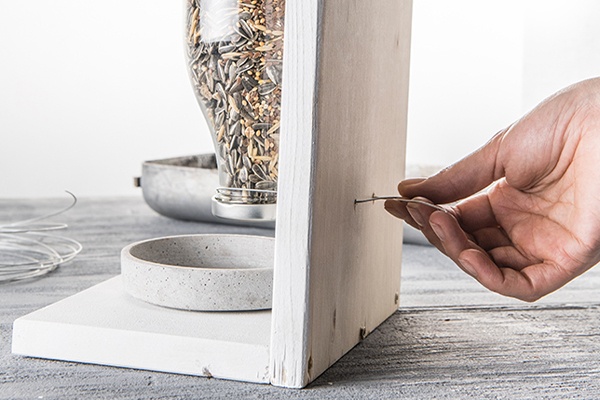 Das Vogelfutter in der Halterung anbringen