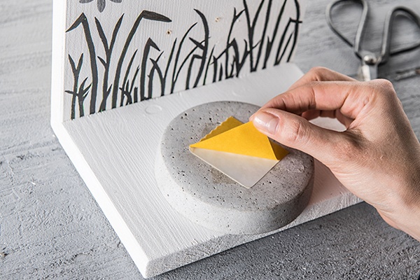 Das Schälchen für das Futter auf der kleinen Platte mit doppelseitigem Klebeband befestigen.