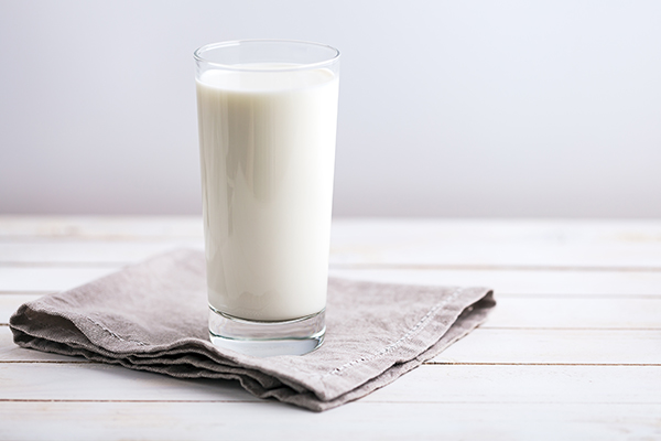 Ein volles Milchglas steht auf  einem Tisch.