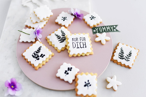 Individuell verzierte Kekse verteilt auf und neben einem Teller