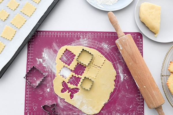 Der ausgerollte Plätzchenteig wird mit unterschiedlichen Formen ausgestochen und auf dem Blech verteilt