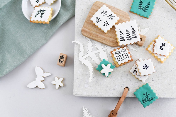 Das Ergebnis sind die bestempelten Kekse in verschiedenen Formen und Farben, verteilt neben der Dekoration