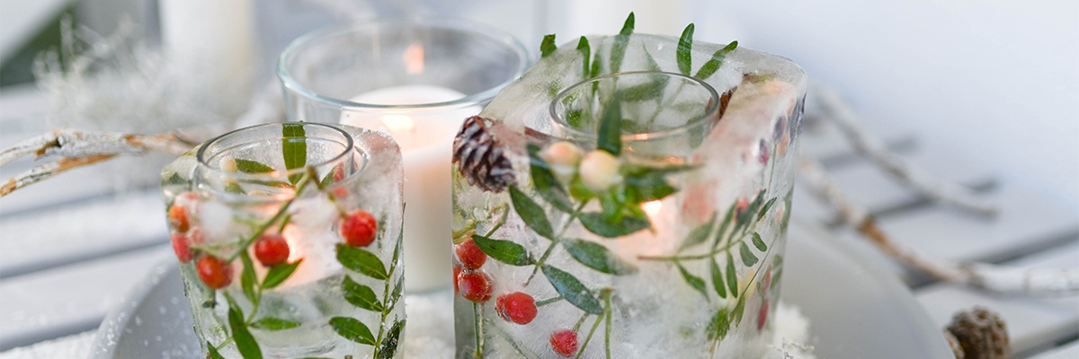 Teelichter in einem ausgehölten Eisbalken mit Hagebutten verziert.