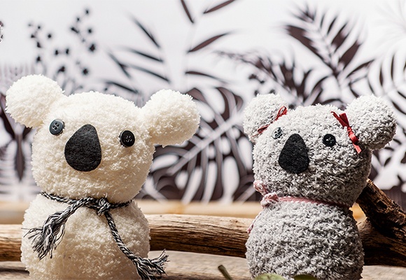 Koala-Plüschbär platziert auf einem dekoriertem Hintergrund mit Blättern und Ästen