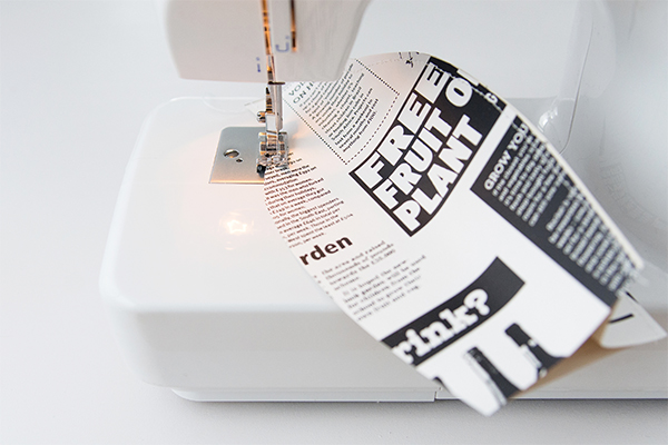 Zeitungspapier in Form einer Vase wird zusammengenäht.