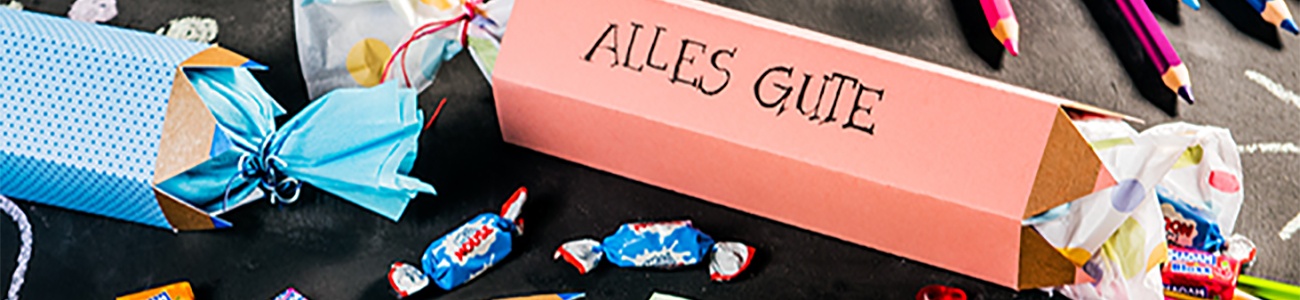 Bunte DIY-Schultüten und Süßigkeiten auf einer beschrifteten Kreidetafel