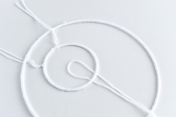 Den kleinen Ring im großen Ring platzieren und mit der Wolle an mindestens drei Stellen einspannen