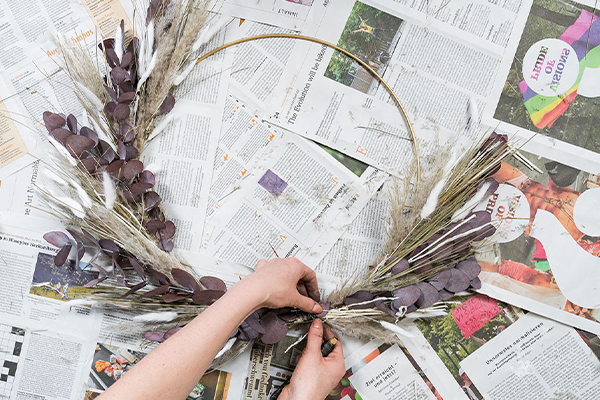Trockenblumen werden auf einen Metallring gebunden.