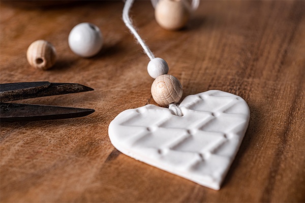 DIY Duft-Anhänger werden mit einem Band und kleinen Holzkugeln dekoriert