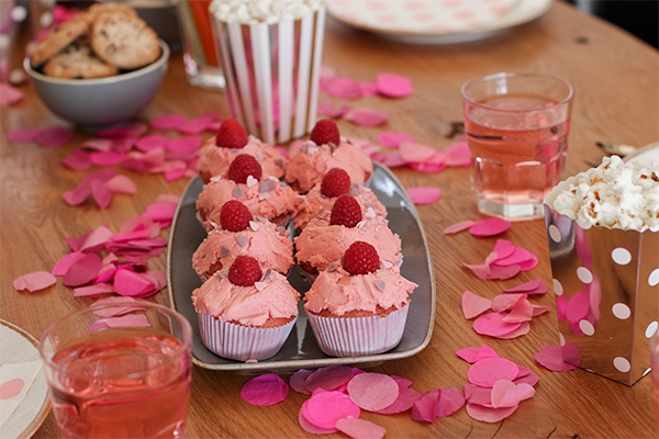 Cupcakes mit rosa Topping und verziert mit Himbeeren  auf dem Teller