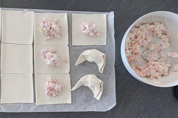 Blätterteig zuschneiden, mit der Käse-Schinken-Füllung befüllen und Kipferl formen