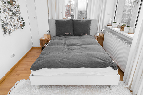 Bett mit grauer Bettwäsche