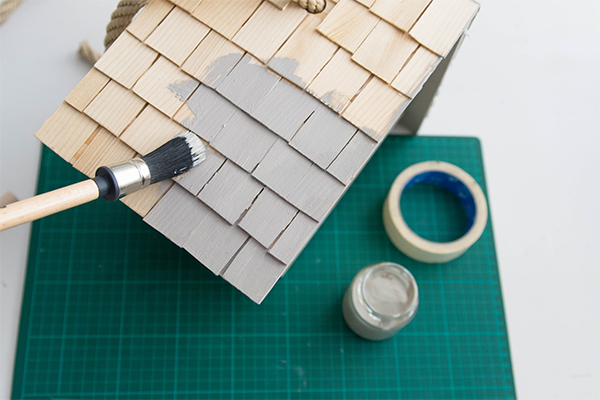 Dach eines Vogelhauses wird grau bemalt.