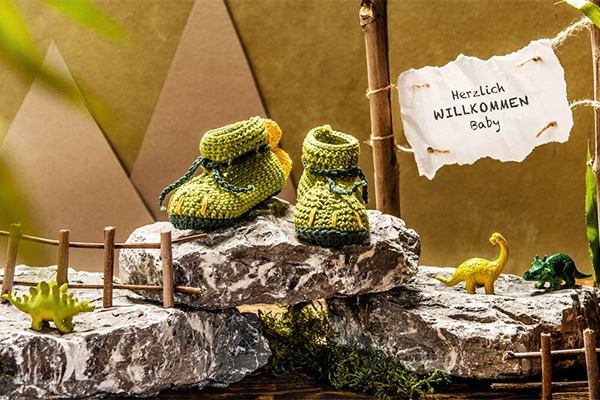 Süßes Baby-Geschenk DIY-Dino-Schühchen dekoriert in einer Dino-Landschaft