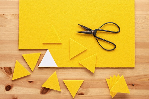 Aus gelbem Papier werden Dreiecke als Dinozacken ausgeschnitten