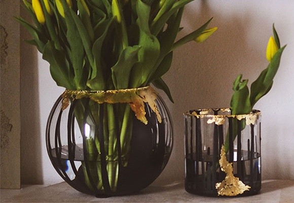 DIY Color Dripping Vasen mit Acrylfarbe und Blattgold, befüllt mit gelben Tulpen als Dekoration auf einem Sideboard mit Lampe