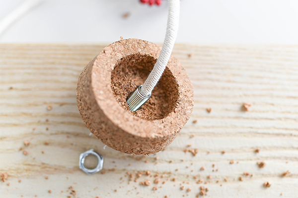 Durch einen Korken ist eine Schnur gefädelt.