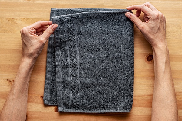 Handtuch an der Längsseite in der Mitte einmal zusammenfalten