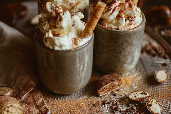 Heiße Schokolade mit Sahnehaube und in grauen Tassen