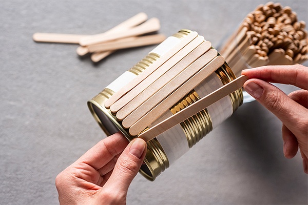 Konservendose der Länge nach mit Holzstäbchen bekleben