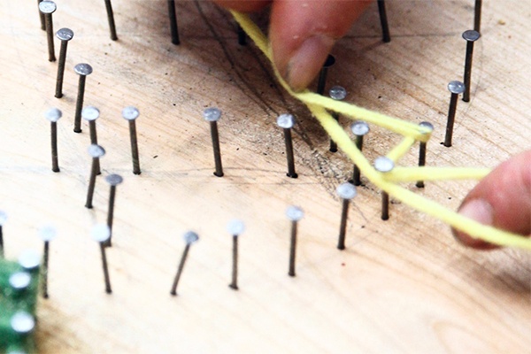 Sommerliche Fadenbilder entlang der einzelnen Nägel mit bunter Wolle drehen