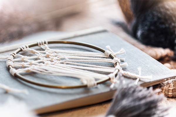 Traumfänger zum Nachmachen mit Fäden als Dekoration auf einem Buch liegend