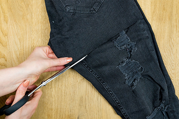 Schwarze Jeans wird geschnitten