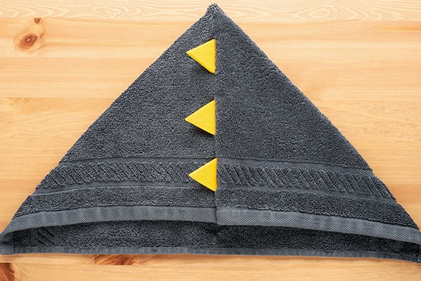 Aus dem Handtuch wird eine Kapuze in Form eines Dreiecks gelegt