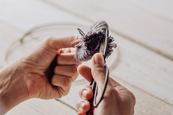 Die Wolle an der Seite aufschneiden, so ergeben sich Bommel für den Traumfänger 