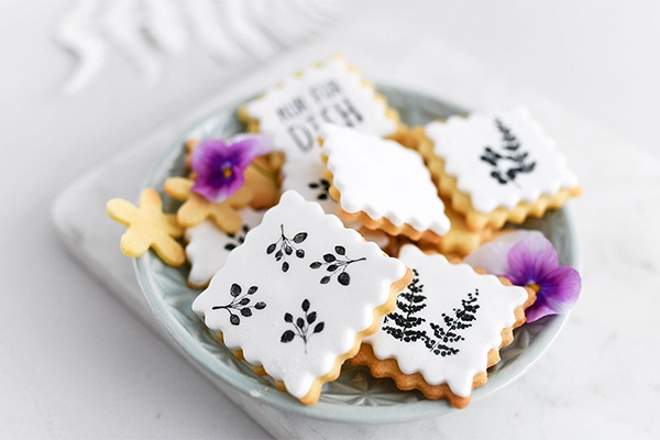 Mit Blüten und Schrift bestempelte Kekse in einer Schüssel