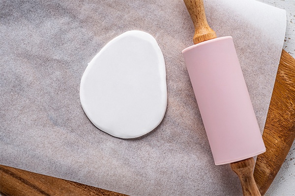 Die Knetmasse mit dem Nudelholz auf Backpapier und einem Holzbrett ausrollen