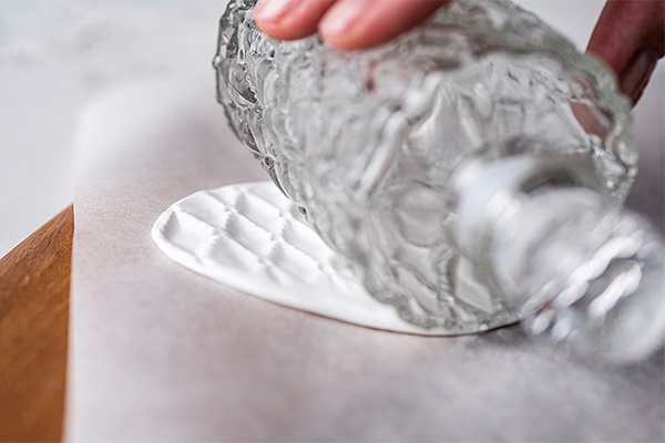 Muster mit einer Glasflasche in die Knetmasse für den DIY Duft-Anhänger kneten