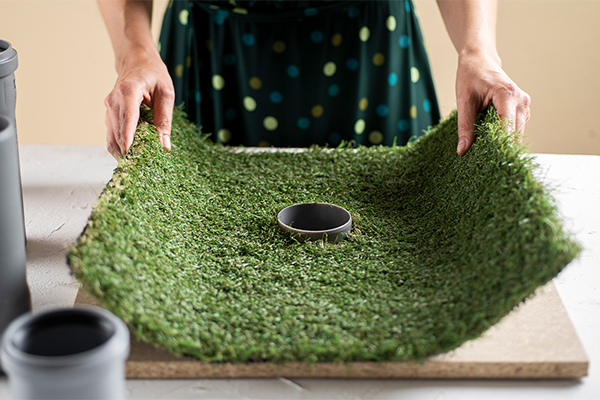 Kunstrasen wird auf eine Holzplatte gelegt