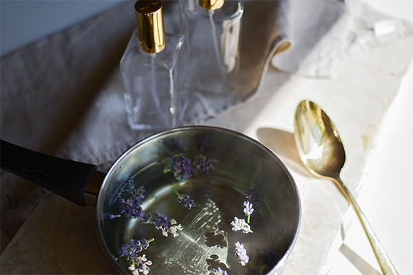 Lavendel mit Wasser in einem Topf, daneben Sprühflaschen zum Abfüllen