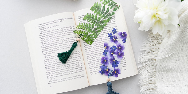DIY Florale Lesezeichen mit gepressten Blüten und Blättern drapiert in einem aufgeklappten Buch
