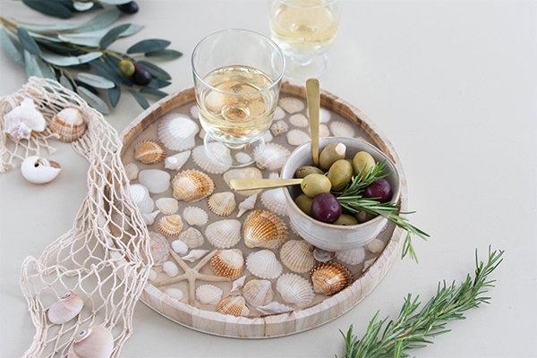 Getränke und Essen auf Tablett mit Muscheln servieren