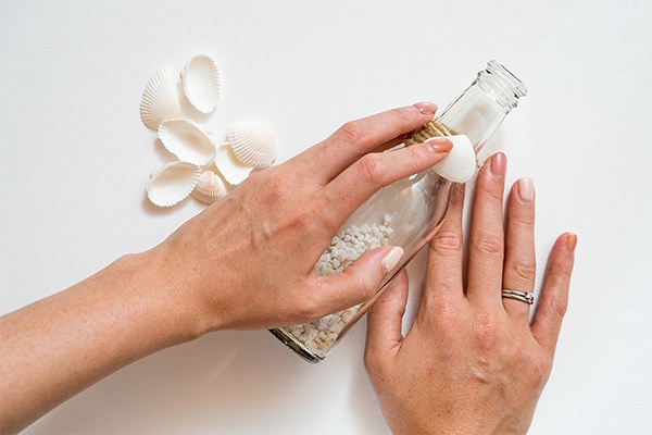 Muscheln und Kordel-Band auf eine Flasche kleben 