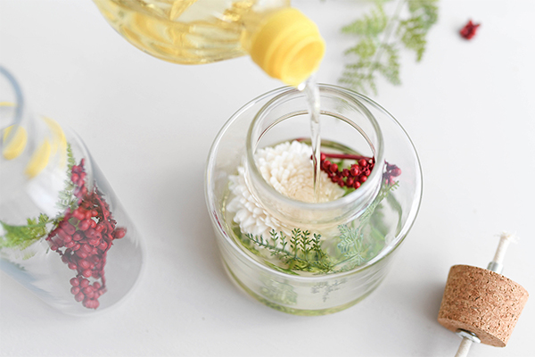 In ein Gefäß mit Blumen wird Öl gefüllt.