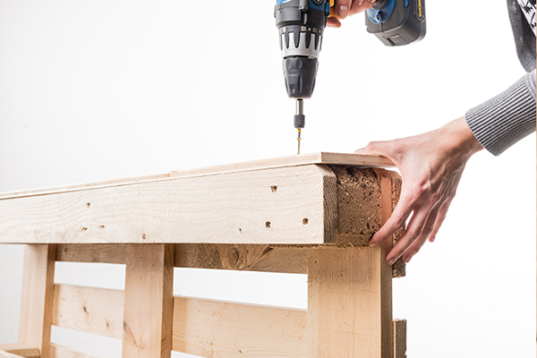 Holzlatte wird auf Palette geschraubt