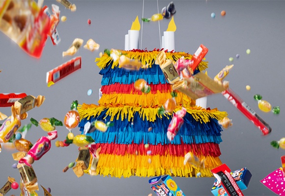 Selbstgemachte, bunte Piñata umgeben von herumfliegenden Süßigkeiten