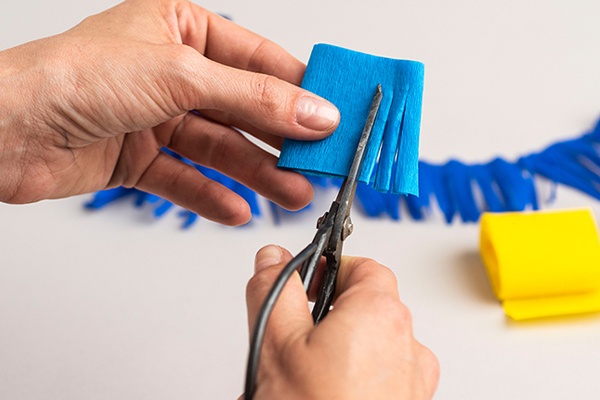 Krepppapier einzeln einschneiden, sodass sich dekorative Fransen ergeben