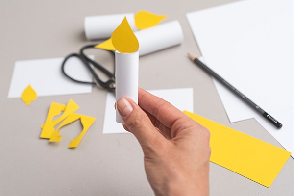 Die bunte Piñata oben mit selbstgebastelten Kerzen aus Karton verzieren