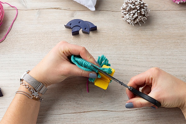 Selbst gemachte Pompons aus Wolle aufschneiden