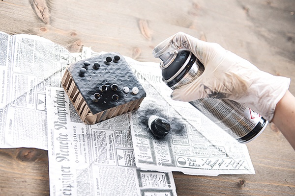 Schraubverschluss und Reißzwecken mit schwarzem Lack besprühen