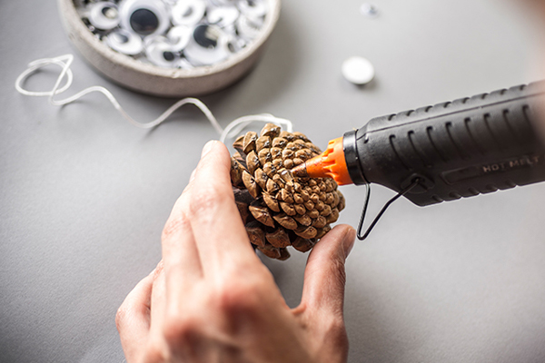 Auf einen Zapfen wird Kleber einer Heißklebepistole angebracht