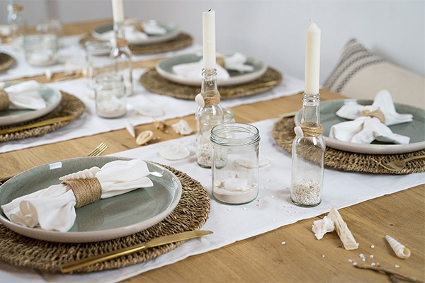 Sommerliche Tischdeko mit Sand, Muscheln und Kerzen 