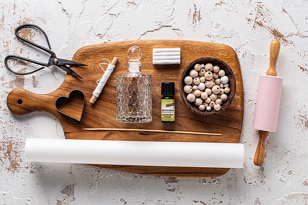 Materialien für den DIY Duft-Anhänger sind Knetmasse, Herzausstecher, Holzkugeln und Backpapier