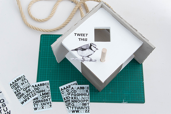 Ein Vogelhaus wird verziert mit einer Aufschrift "Tweet this" und einem Vogel.
