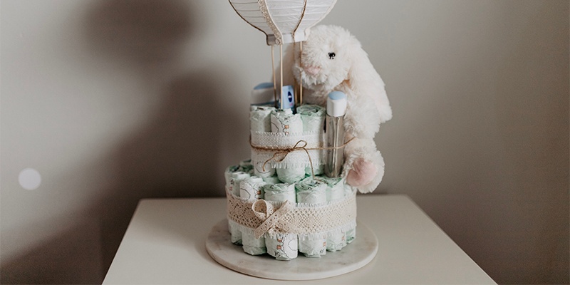 Windeltorte mit weißem Stoffhasen und Papierballon auf einem weißen Tisch