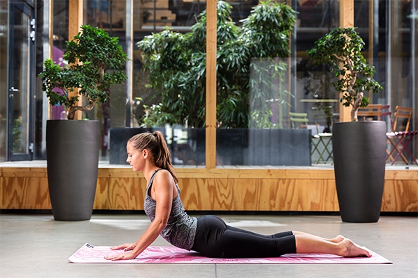 Eine Frau führt die Yoga Übung Kobra aus.